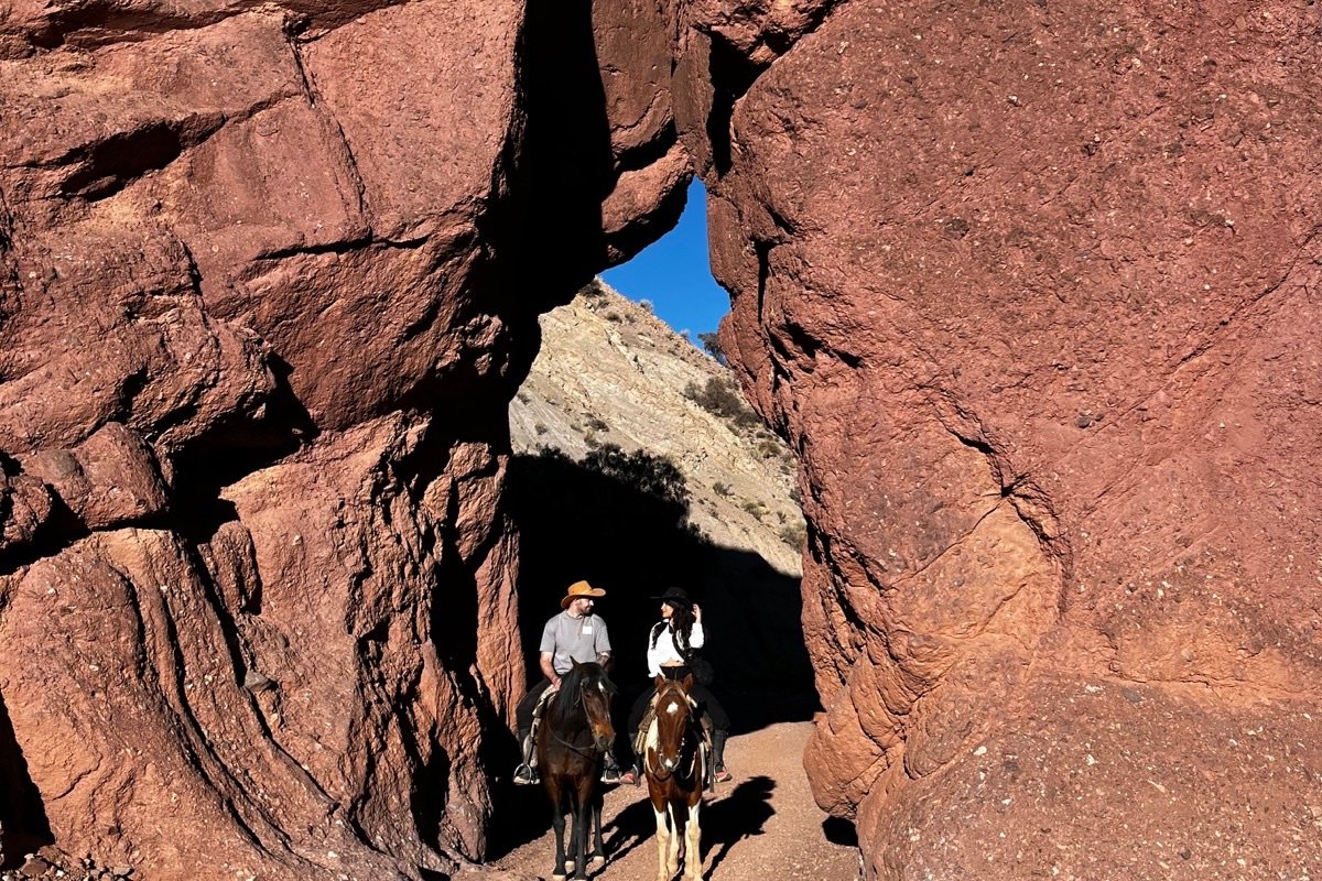 Jinetes atraviesan una abertura entre las rocas rojas de Tupiza