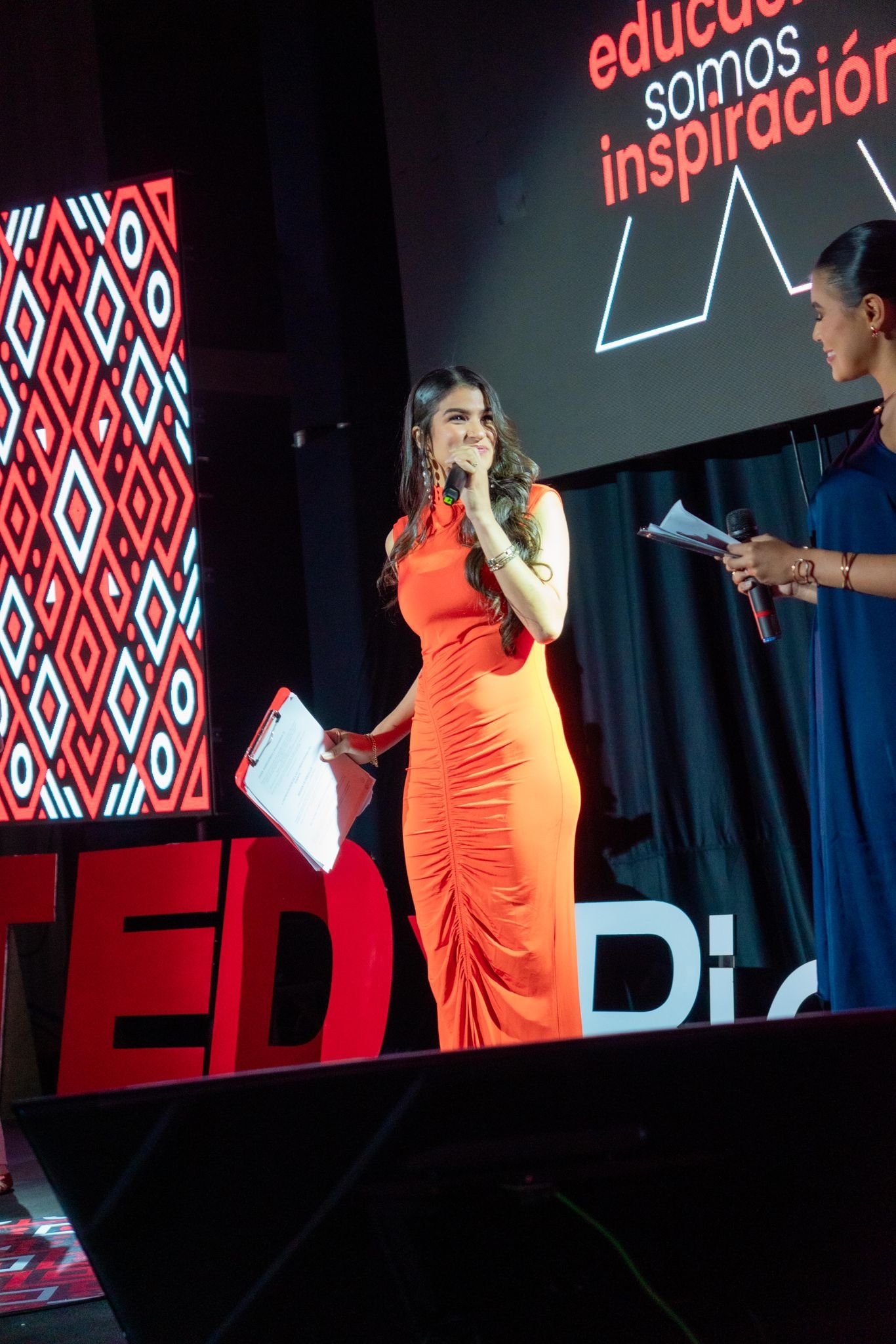 Dana Arredondo hablando con un micrófono en el escenario de TEDx Riohacha.